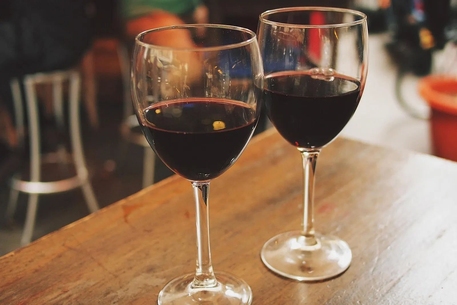 An empty cafe table with two glasses beside warm windows at dusk